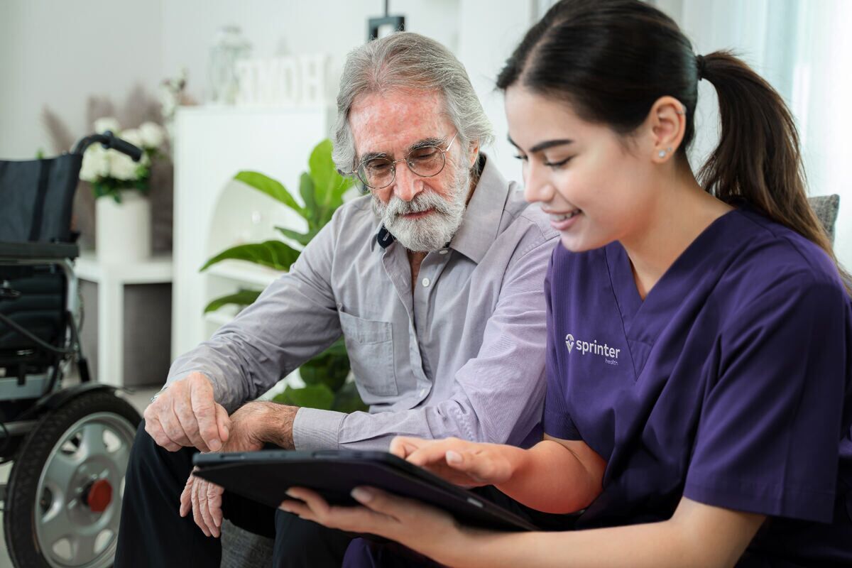 Sprinter Health clinician reviewing care information on a tablet with a senior patient at home